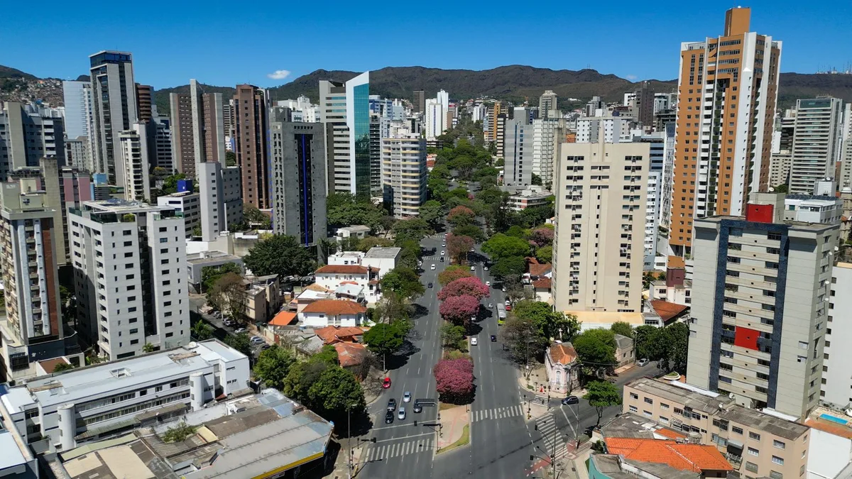 Avenida arborizada em Belo Horizonte com a Serra do Curral ao fundo, o relevo que dá nome ao bairro Serra